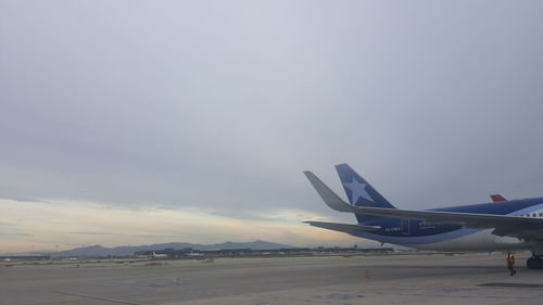 Airplane flying over airport runway against sky