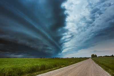 Road amidst field against sky