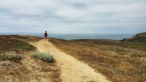 Rear view of woman walking on mountain against sky