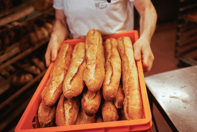 Midsection of man storing baguette bread