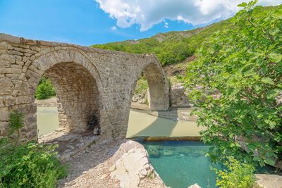 Arch bridge over mountain against sky