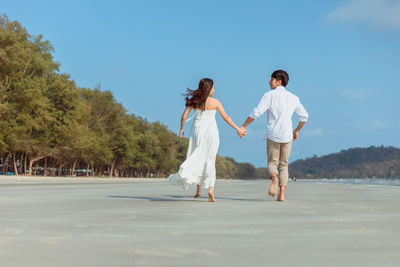 Rear view of couple walking on road