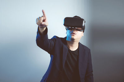 Close-up of man wearing virtual reality simulator against gray background