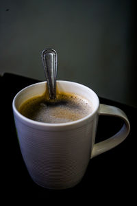 Close-up of coffee cup on table against black background