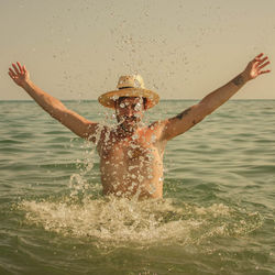 Man splashing water in sea during sunset