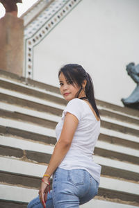 An asian woman in a white t-shirt looking at a camera at the wat arun temple while traveling
