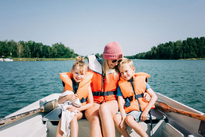 Mother sat on a boat hugging her kids happily in summer in sweden
