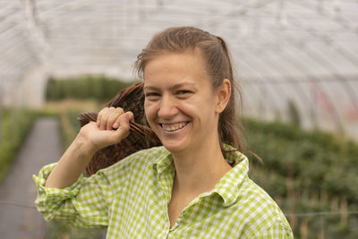 Young woman working as vegetable grower or farmer in a greenhouse