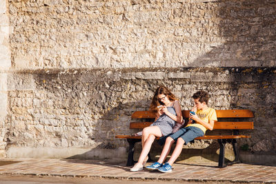 Full length of a woman sitting on wall