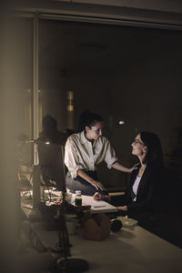 Businesswoman planning strategy with female colleague while working last minute in office