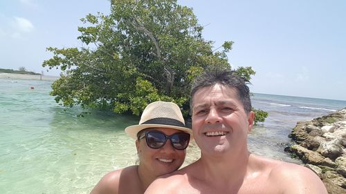 Portrait of smiling couple swimming in sea against sky