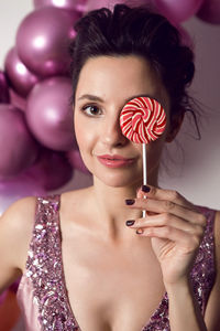 Girl in pink dress holding round striped candy