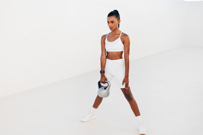 Full length of young woman standing against white background