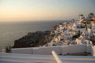 Buildings by sea against clear sky during sunset