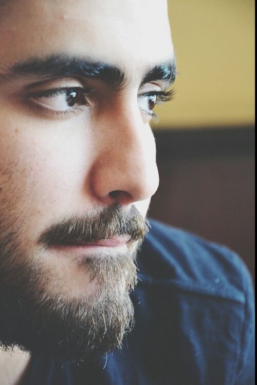 headshot, close-up, human face, portrait, lifestyles, looking at camera, focus on foreground, indoors, person, front view, young adult, head and shoulders, leisure activity, contemplation, part of, serious, beard