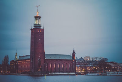 Lighthouse by sea against sky at night