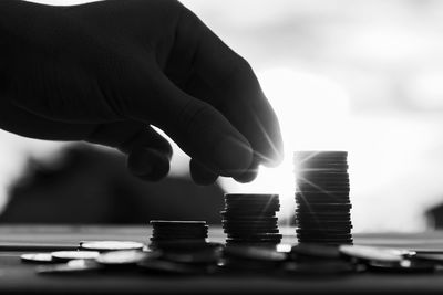 Cropped hand of person stacking coins at table