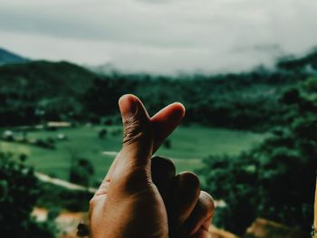 Close-up of human hand against sky