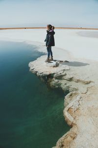 Full length of woman standing by lake against clear sky at atacama desert