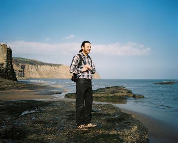 Full length of man standing at beach against sky