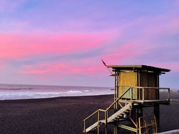 Lifeguard hut on beach against sky during sunset