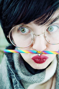 Close-up of hipster woman wearing eyeglasses with colorful drinking straw