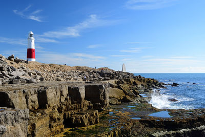 Lighthouse on mountain by sea against sky