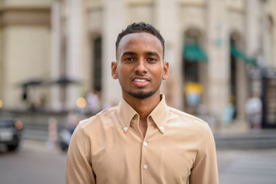 Portrait of young man standing against city