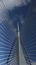 Low angle view of suspension bridge against cloudy sky