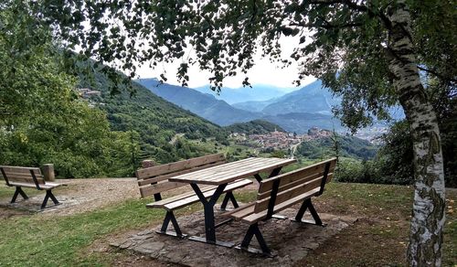 Empty bench on table against mountains