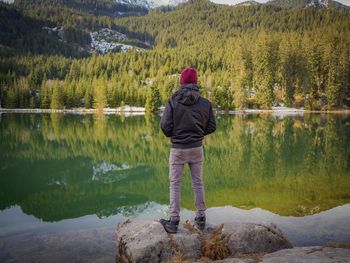 Rear view of man standing by lake against mountain