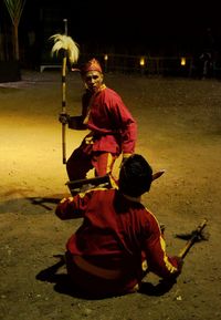 Full length of man sitting on street at night