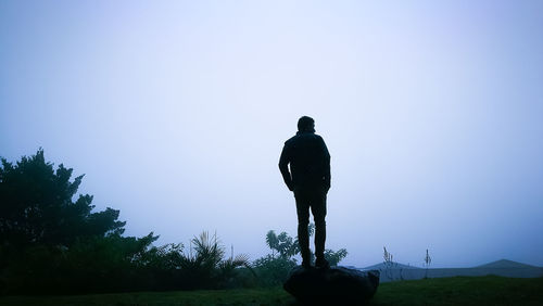 Rear view of silhouette man standing on field against sky