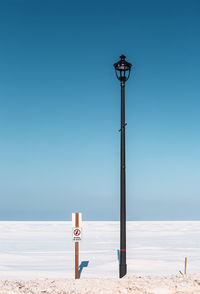 Street light on beach against clear blue sky