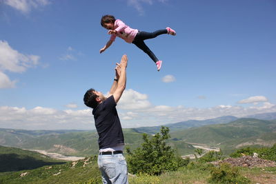 Full length of man with arms raised against mountains