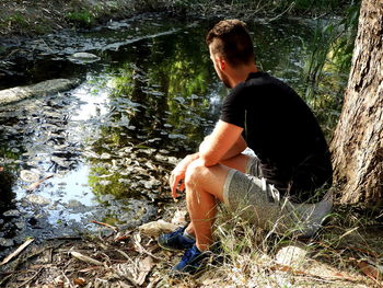 Man sitting on rock in forest