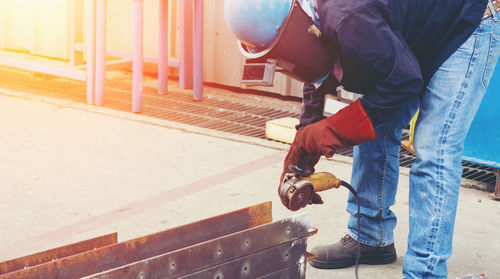 Construction worker grinding metal at site