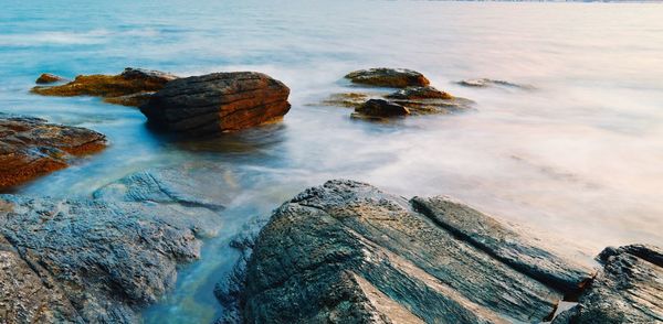 Close-up of rocks in sea against sky