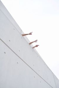 Low angle view of human hands against clear sky