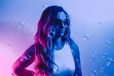 Portrait of young woman with neon lights and sunglasses