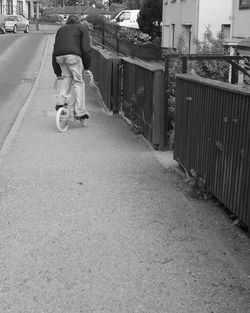 Rear view of man riding bicycle on road