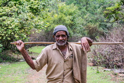 Portrait of senior man holding stick on land