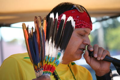 Close-up of mature man talking on microphone while holding feathers