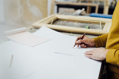 Craftsman drawing at workbench in workshop