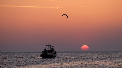 Silhouette ship in sea against sky during sunset