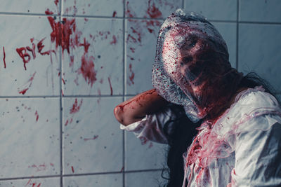 Portrait of woman with red paint against wall