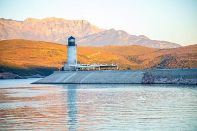 Lighthouse by lake against sky