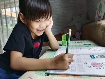 Girl drawing on book at home