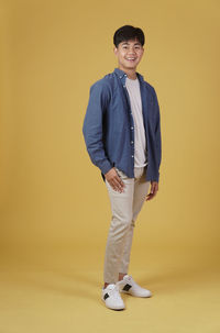 Portrait of a smiling man standing against yellow background