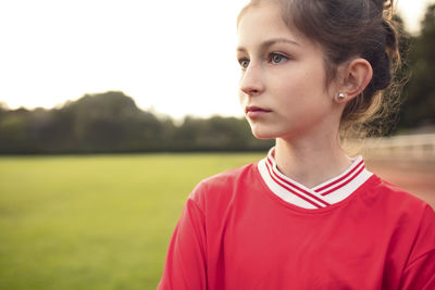 Female soccer player standing on field against sky